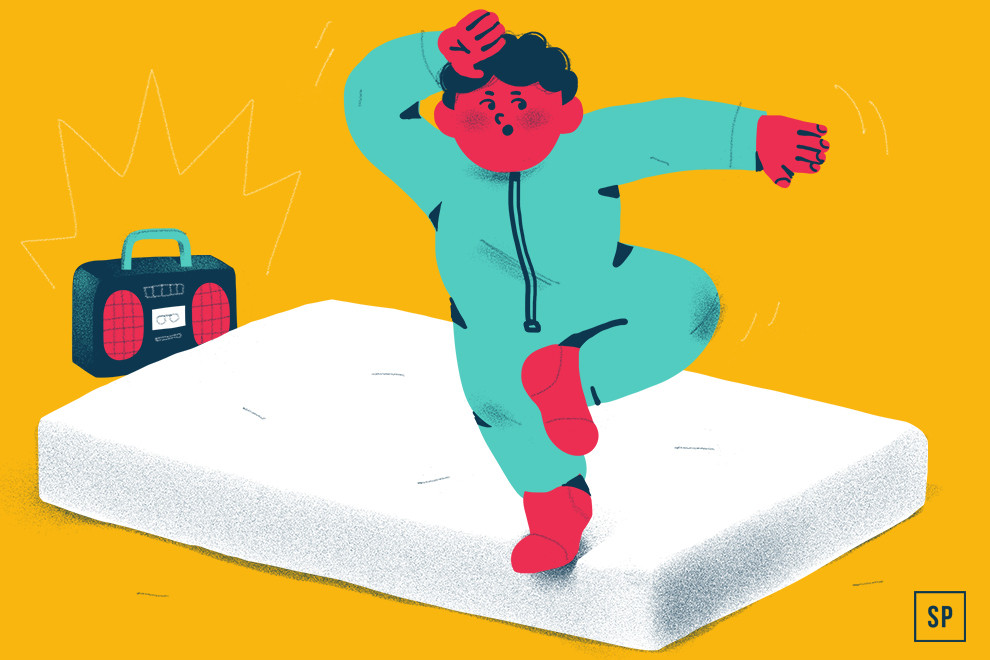 Eine Person in einem blaugrünen Overall tanzt energisch auf einer weißen Babymatratze, ein Bein angehoben und einen Arm auf der Stirn. In der Nähe spielt ein Ghettoblaster Musik, die vor einem leuchtend gelben Hintergrund wie eine lebendige Ratgeberszene wirkt.