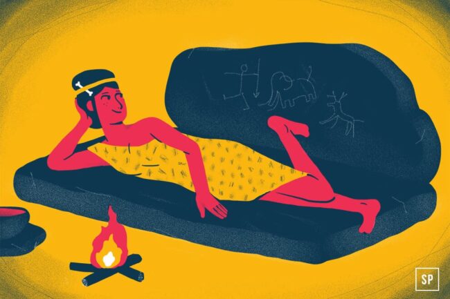 Eine Person in einem gelben Gewand lehnt auf einer Matratze auf einem dunkelblauen Felsen in der Nähe eines kleinen Lagerfeuers. Auf dem Felsen hinter ihr sind einfache Tierhöhlenzeichnungen vor einem gelben Hintergrund eingraviert.