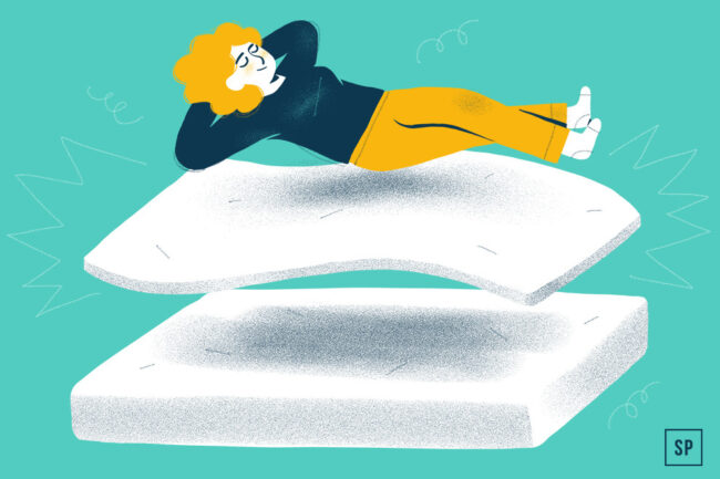 Eine Person mit lockigem Haar, die ein schwarzes Oberteil und eine gelbe Hose trägt, entspannt sich mit den Händen hinter dem Kopf, während sie auf einem Matratzen-Topper über einer anderen Matratze liegt - eine sinnvolle Ergänzung - vor einem tealfarbenen Hintergrund.