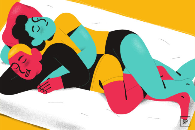 Zwei Personen mit heller Hautfarbe liegen in Löffelchenstellung auf einem Bett und zeigen eine der Schlafpositionen bei Paaren und ihre Bedeutung für die Beziehung. Beide tragen Shorts und T-Shirts, vor einem gelben Hintergrund und Bettzeug.