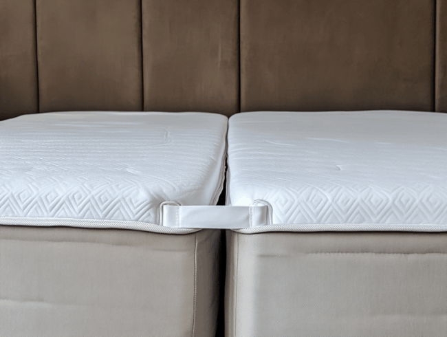 zwei nebeneinander liegende Matratzen, die durch ein weißes Band verbunden werden