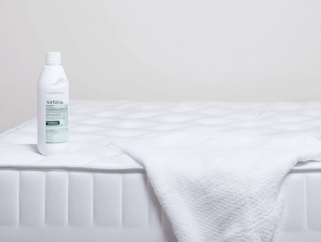Eine weiße Matratze und eine Flasche Desinfektionsmittel, bereit die Matratze zu desinfizieren