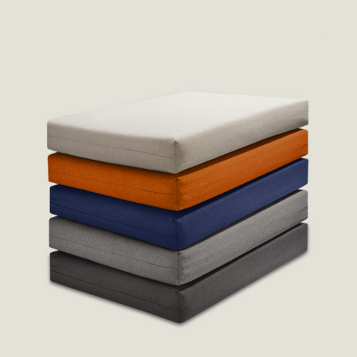 Ein Stapel von fünf Stoffmustern für Polster in den Farben Hellbeige, Orange, Blau, Hellgrau und Dunkelgrau ist ordentlich vor einem unifarbenen Hintergrund arrangiert und zeigt die Vielfalt der verfügbaren Polsterstoffmuster.