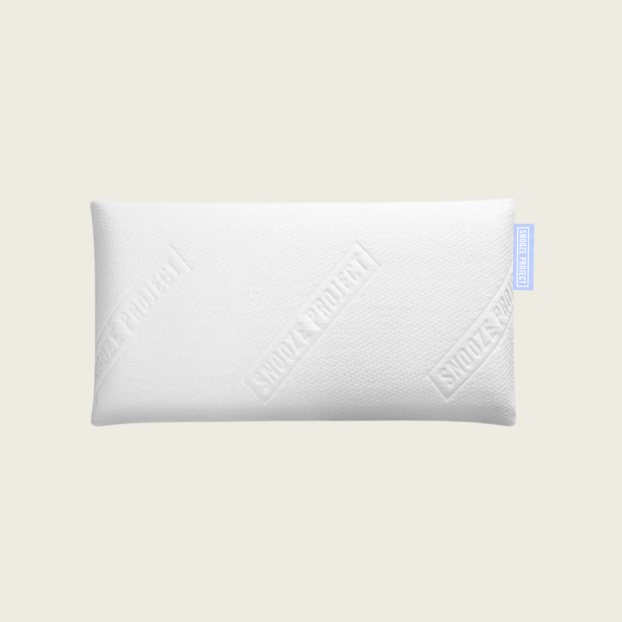 Ein rechteckiges weißes Kissen mit einem subtilen strukturierten Muster und geprägtem SNOOZE PROJECT-Text, der vor einem schlichten hellen Hintergrund gezeigt wird. An einer Seite ist ein kleines blaues Stoffschildchen angebracht.