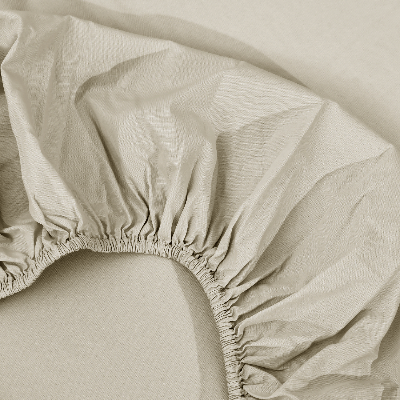 spannbettlaken nach maß beige 2 Eine Nahaufnahme eines hellbeigen Spannbettlakens mit gerafften, elastischen Rändern vor einem passenden Hintergrund.