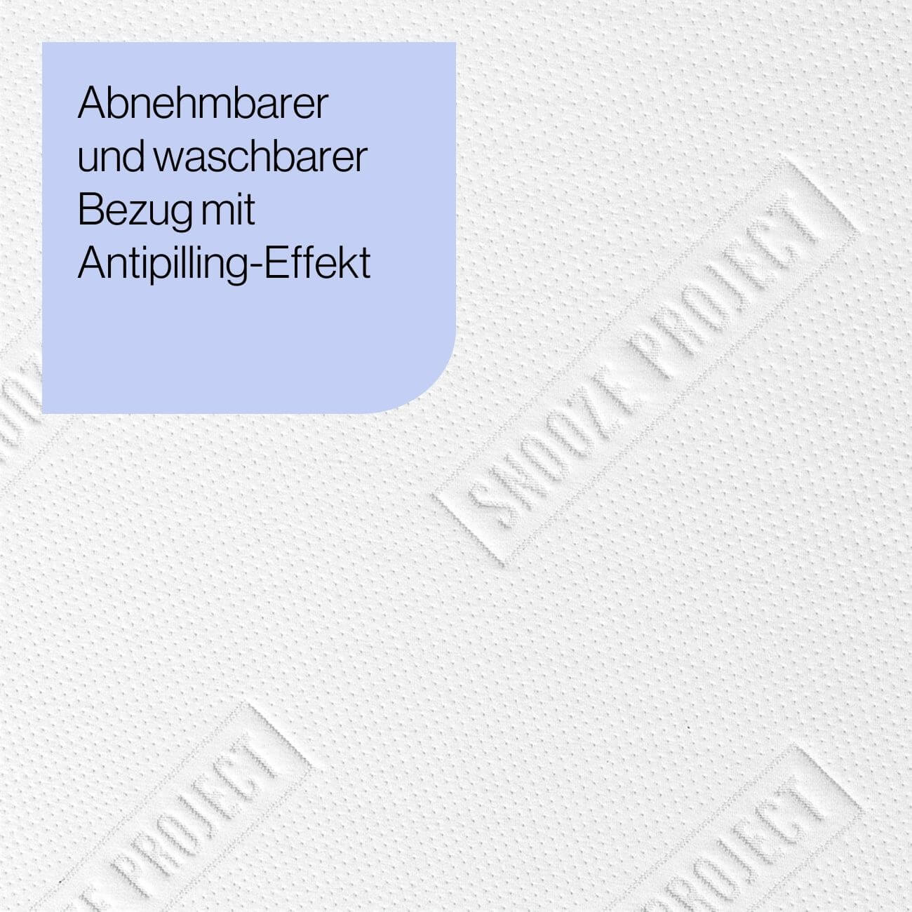 8 Eine hellviolette Schachtel mit dem deutschen Text Abnehmbarer und waschbarer Bezug mit Antipilling-Effekt auf einem strukturierten weißen Hintergrund mit dezenter Prägung des Wortes SNOOZE PROJECT.
