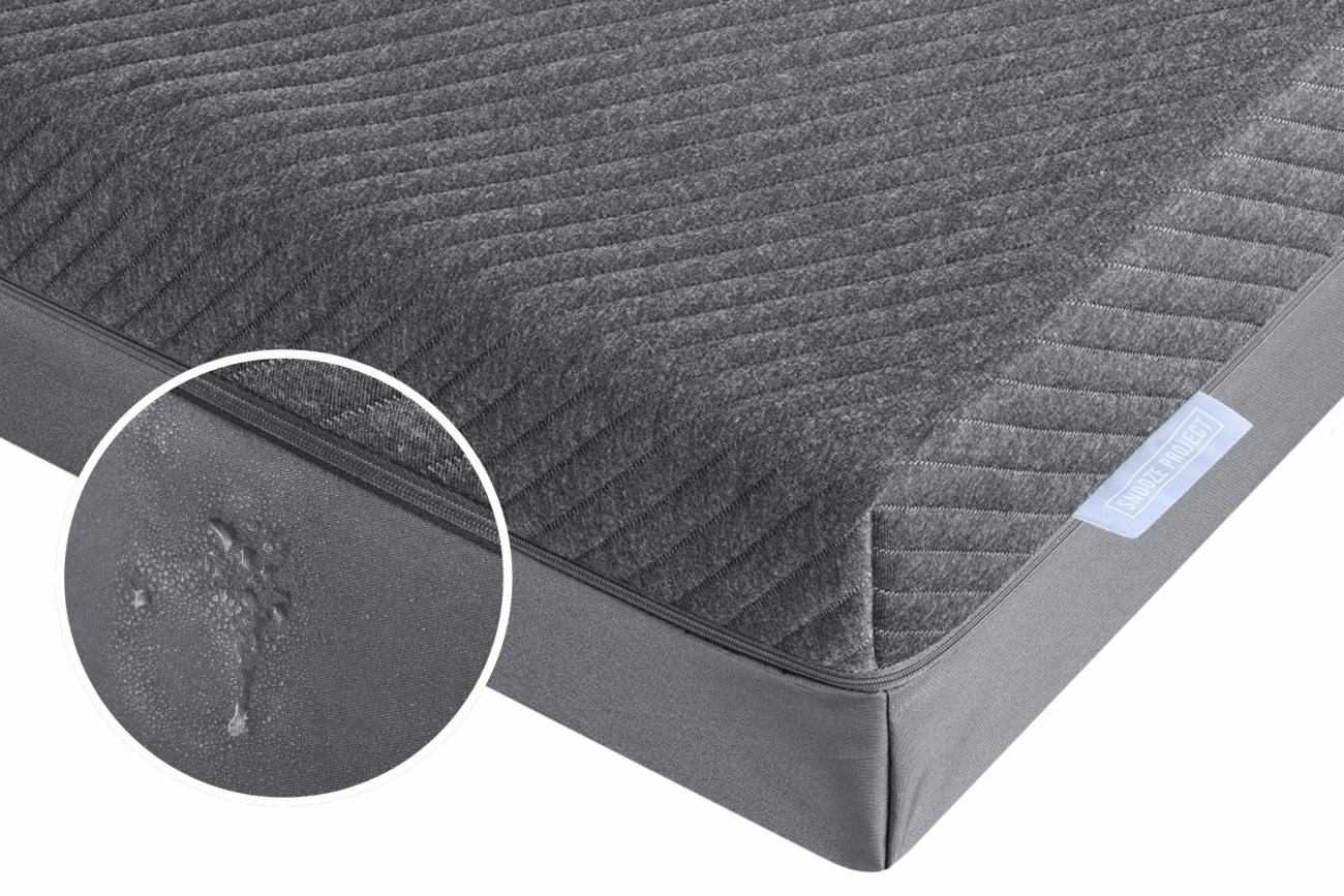 Eine Nahaufnahme einer grauen Matratze mit einem gezoomten Ausschnitt zeigt einen Fleck oder einen nassen Fleck, der die Beschädigung an der Seite hervorhebt - und veranschaulicht, warum Matratzen nach Maß helfen kann, solche Probleme zu vermeiden, um eine saubere Schlaferlebniswelt zu schaffen.