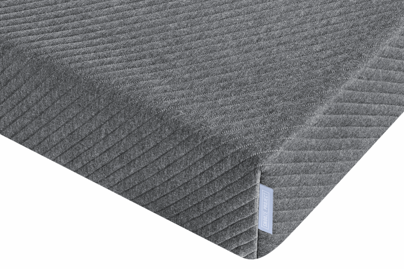 Nahaufnahme einer rechteckigen, grauen Memory-Foam-Matratze mit einem strukturierten, diagonal gestreiften Stoffbezug und einem kleinen Stoffetikett an der Seite - Perfekt für Matratzen nach Maß aus unserem Konfigurator.