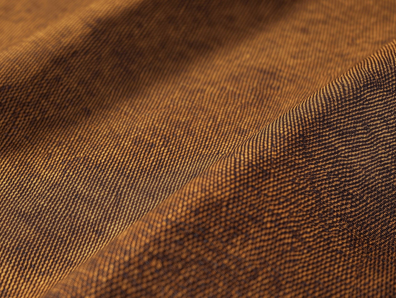 Nahaufnahme eines braunen Mako-Batist-Gewebes mit feinen diagonalen Linien und sichtbarer Bindung, das weiche Falten und eine sanft gewellte Oberfläche aufweist.