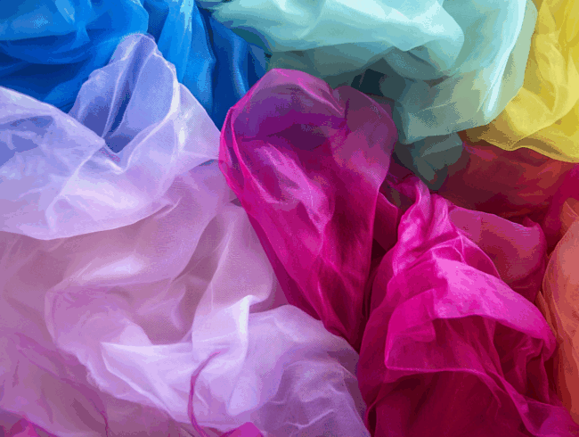 Buntes, durchsichtiges Polyamid-Gewebe in Blau-, Grün-, Rosa-, Violett- und Weißtönen, das sich überlagert und überlappt, um ein weiches, fließendes und strukturiertes abstraktes Muster zu erzeugen.