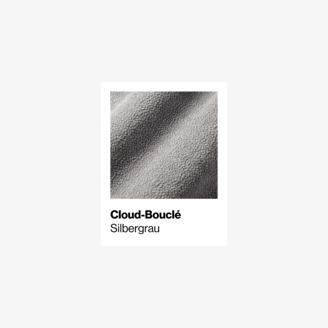 Nahaufnahme eines Cloud-Bouclé-Stoffes in einem hellen Silbergrau mit der Aufschrift Cloud-Bouclé Silbergrau auf weißem Hintergrund. Die Textur erscheint weich und leicht holprig.