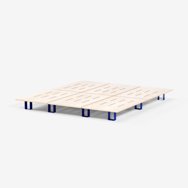 Ein minimalistisches Bettgestell aus hellem Holz mit horizontalen Latten und kurzen, blauen, rechteckigen Beinen, das auf einem schlichten weißen Hintergrund abgebildet ist.