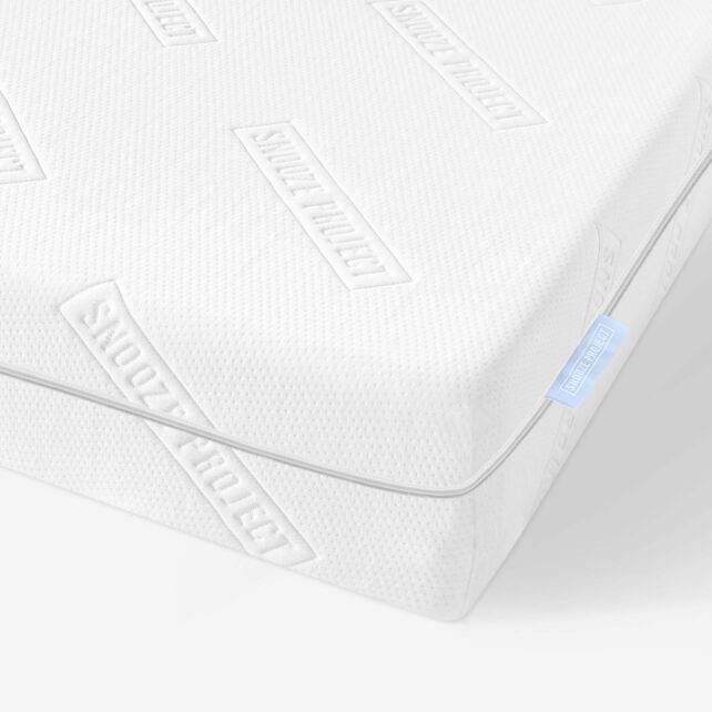 Nahaufnahme einer weißen Matratze mit strukturierter Oberfläche, auf der wiederholt der Schriftzug SNOOZE PROJECT eingeprägt ist, sowie ein kleines blaues Stoffetikett in der Ecke.