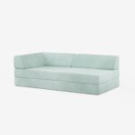 Ein modernes, hellblau gepolstertes Sofa mit niedriger Rückenlehne und Armlehne auf der linken Seite, vor einem schlichten weißen Hintergrund.