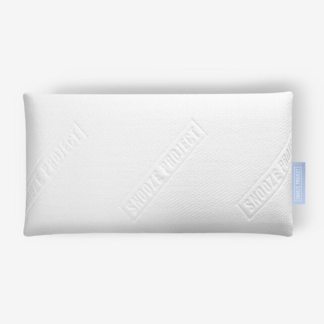 Ein rechteckiges, weißes Kissen mit strukturierter Oberfläche und dem in diagonalen Linien geprägten Schriftzug SNOOZE PROJECT; auf der rechten Seite ist ein blauer Stoffanhänger angebracht.